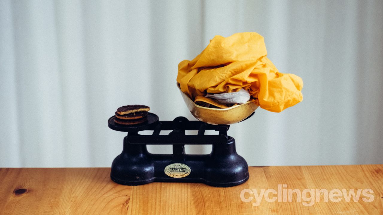 A pile of yellow fabric on a set of vintage scales against some chocolate biscuits