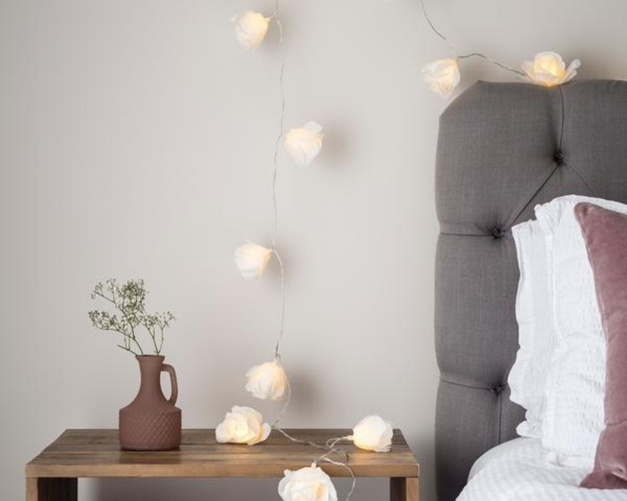 Lights4fun Warm White LED Juliet Rose Fairy Lights draped around bed with grey headboard