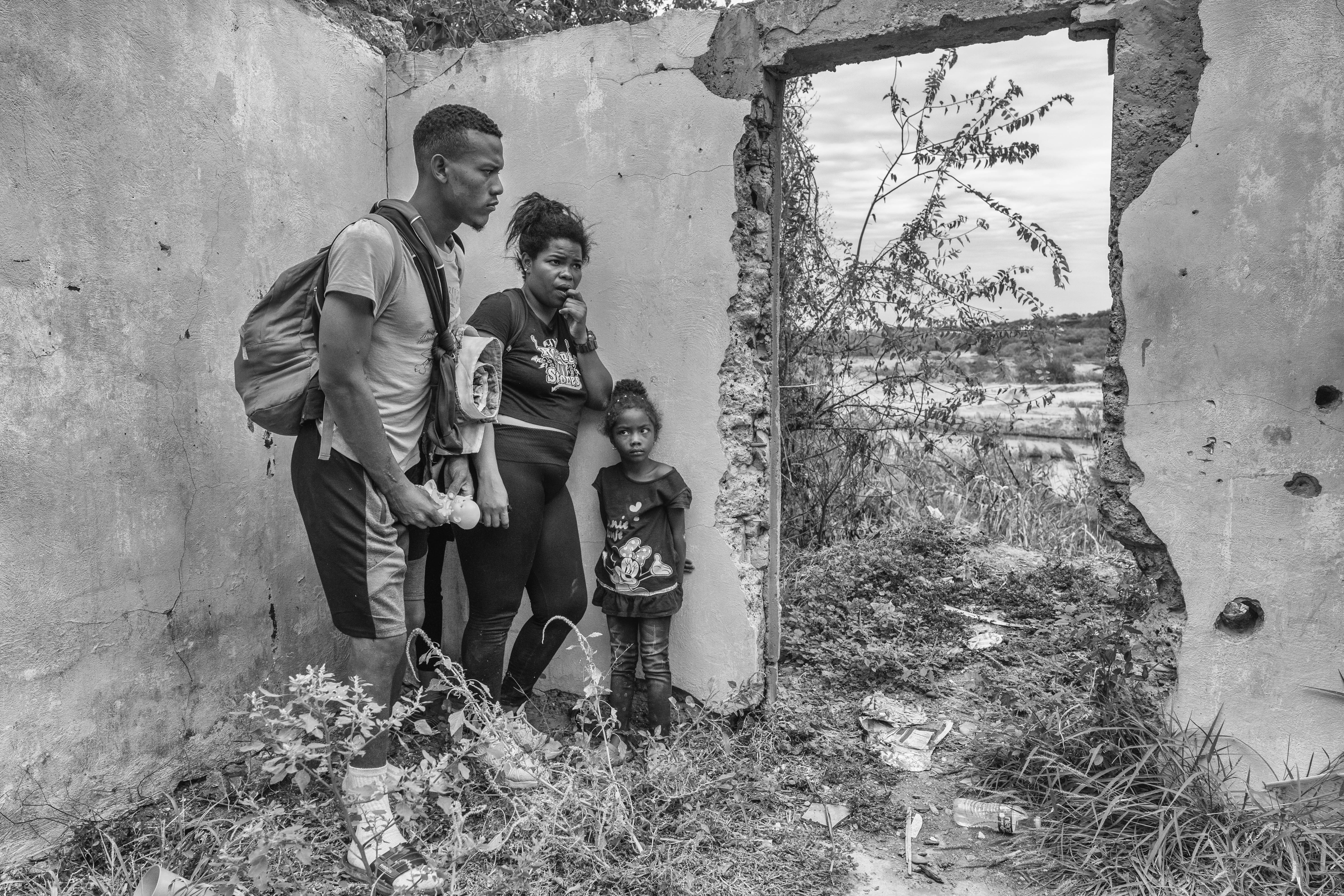 Eddie, Carolina and their four-year-old daughter Valentina, hide inside of an abandoned house before reaching the Rio Bravoin Piedras Negras, Mexico 2023. From the series “The Two Walls”