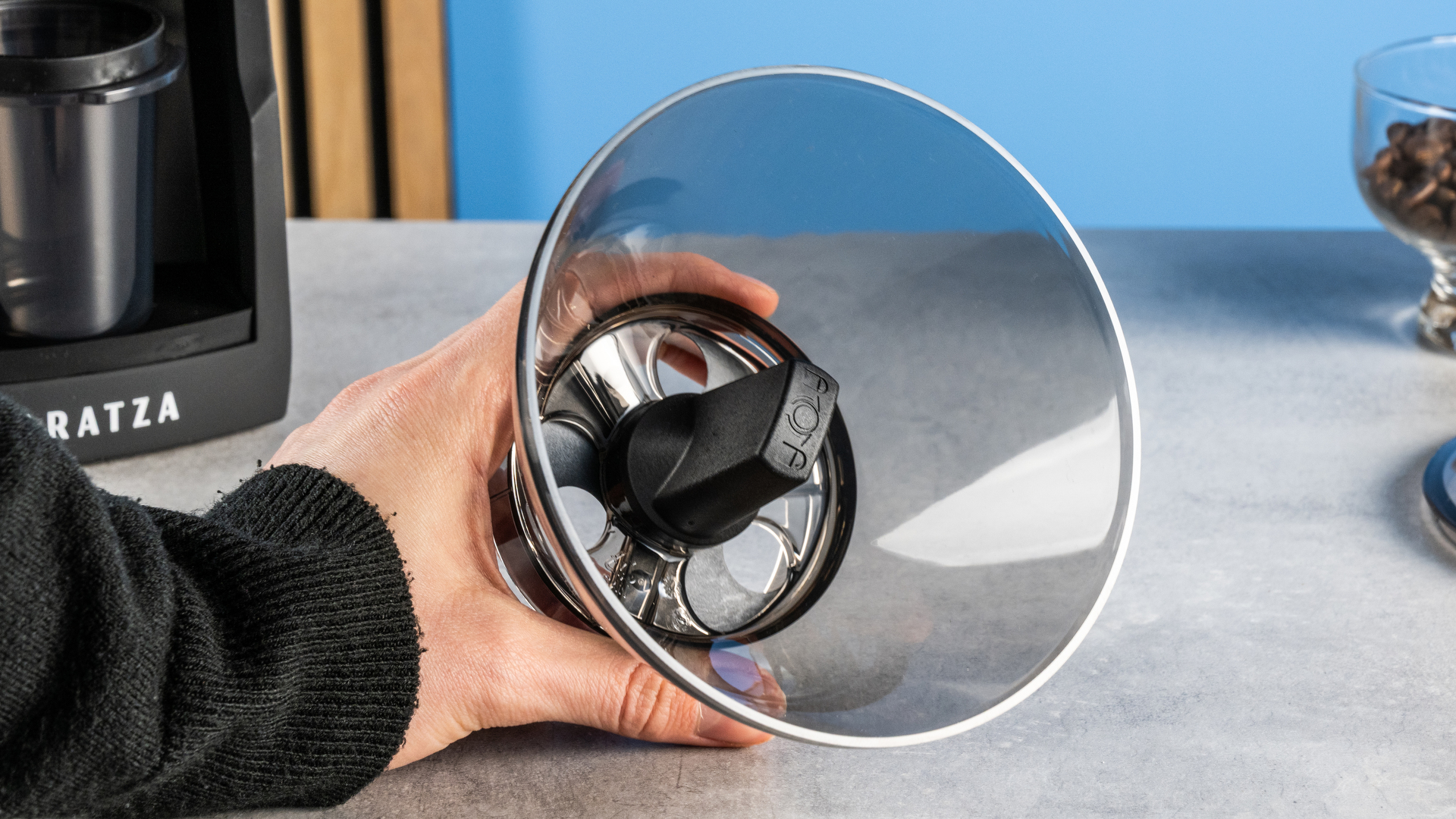 the baratza encore esp pro coffee grinder photographed against a blue tom's guide background with a bag of coffee to the side and showing the grinder in action