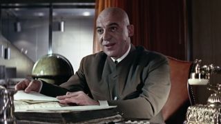 Telly Savalas showing off records on his desk in On Her Majesty's Secret Service.