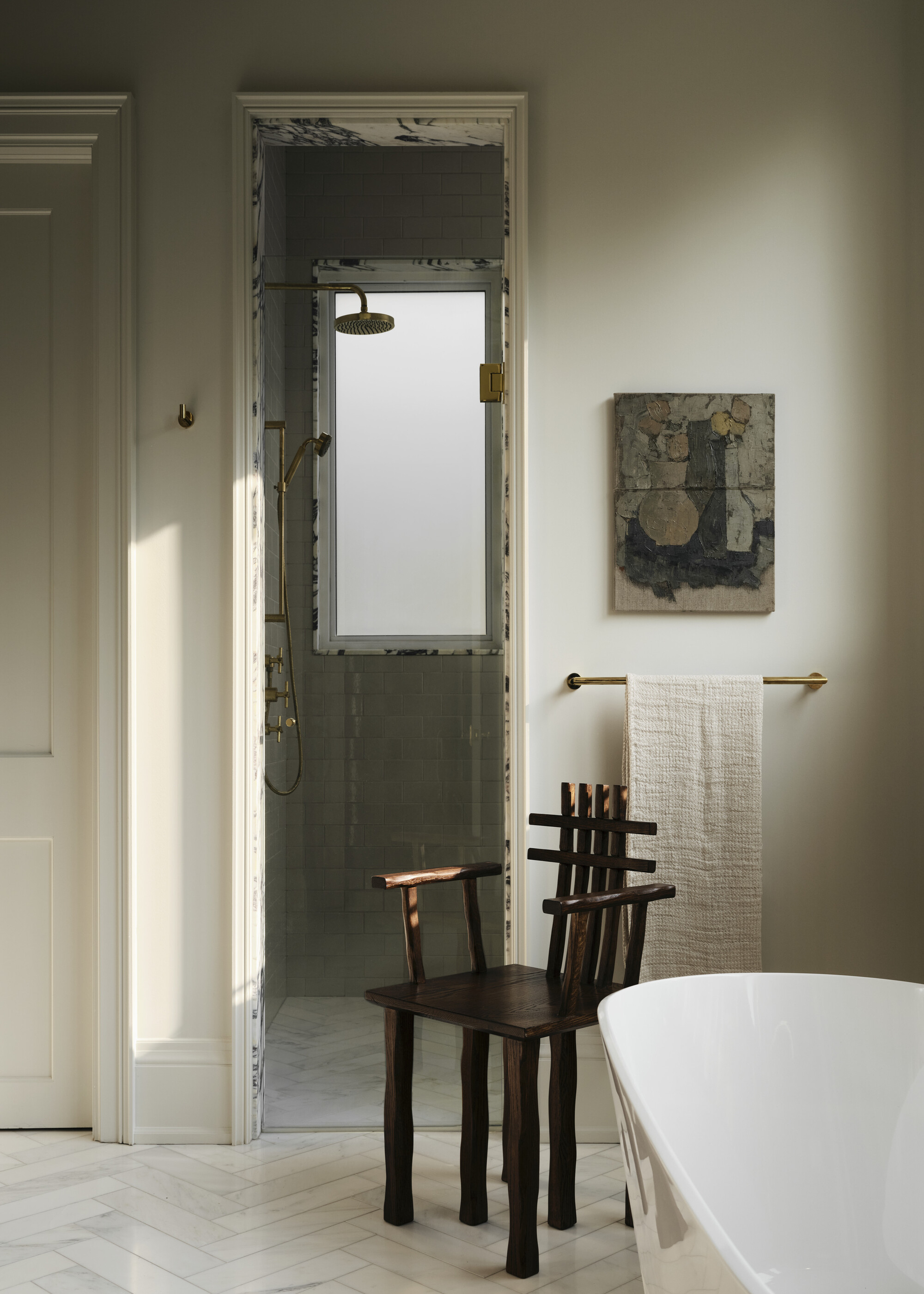 A bathroom with a view into a walk-in shower with a marble door frame