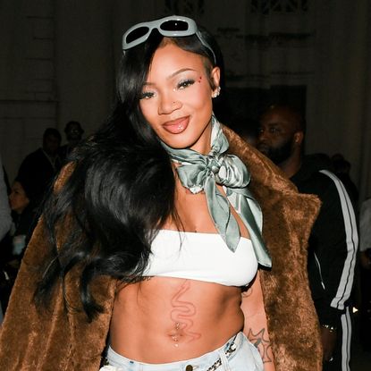 GloRilla wearing a bandeau top with jeans and a fur coat