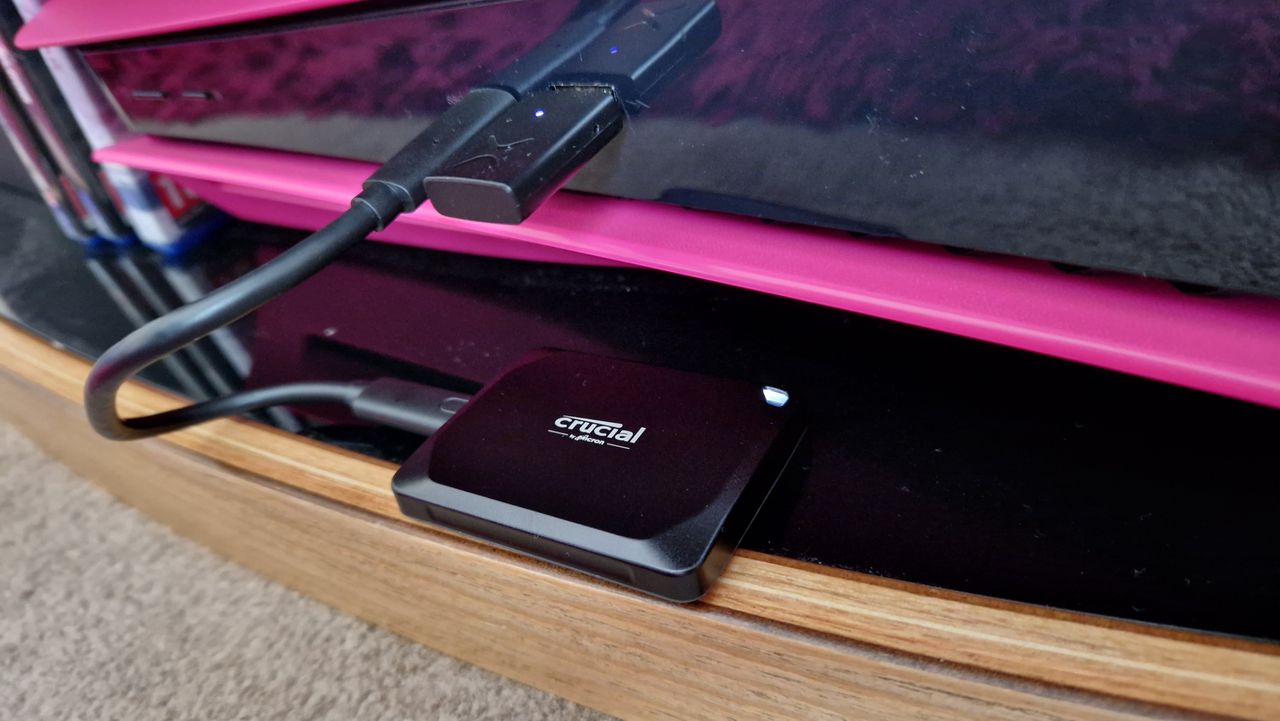 Crucial X10 Pro plugged into a PS5, sitting on a TV stand