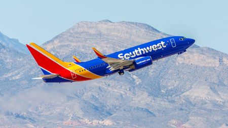 A Southwest Airlines plane lifting off, with mountains in the background