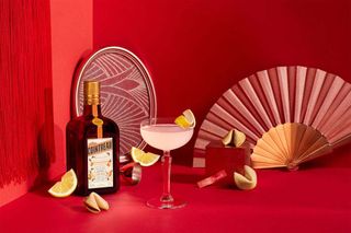 Cointreau bottle and cocktail against red background with fans and fortune cookies