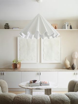 White living room with built-in units, white textured artwork and white ruffled pendant light
