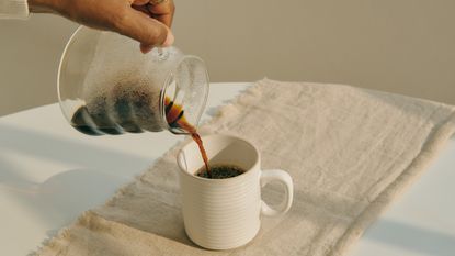 Pouring black coffee from pot into mug