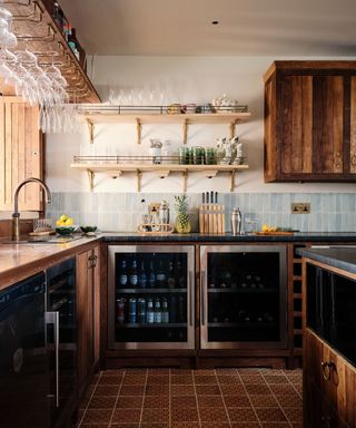 A log cabin kitchen with wood cabinetry, pale blue wall tiles, and open shelving