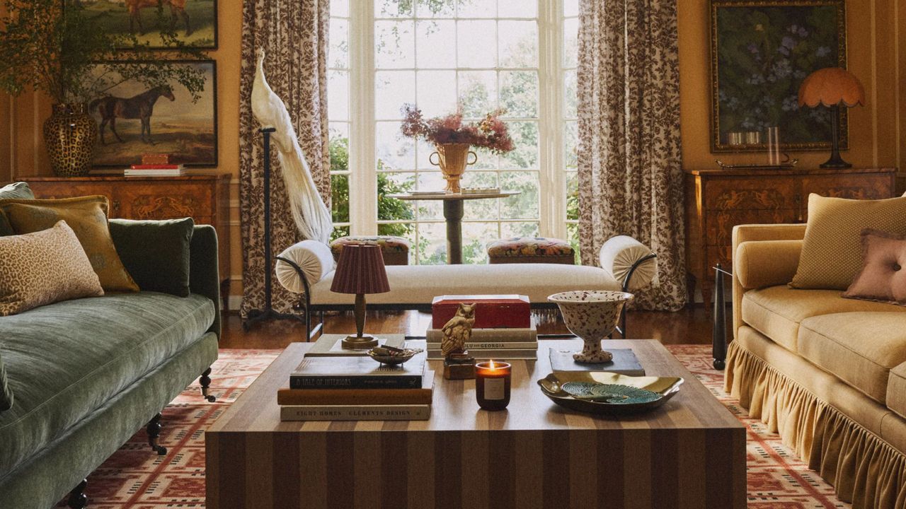 Richly layered fall living room featuring jewel-toned sofas, a striped coffee table, equestrian wall art, and several portable lamps.