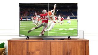 A contemporary LED TV displaying a football game, and the picture is divided in the middle to dramatically illustrate the difference between a Dolby Vision-enhanced picture and a standard broadcast