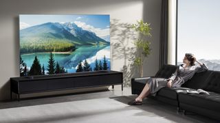 TCL QM8K showing image of mountains in living room with woman watching