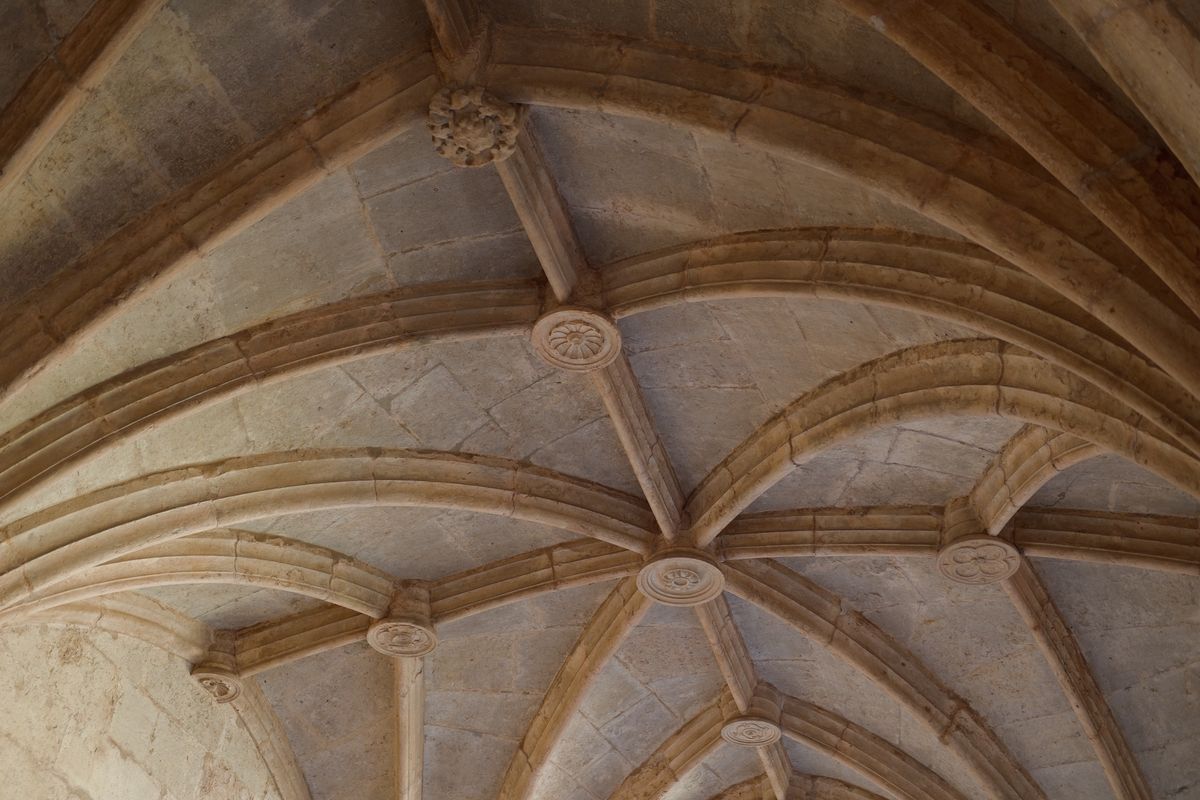 Close-up of a historic rib-vaulted stone ceiling with carved circular bosses.