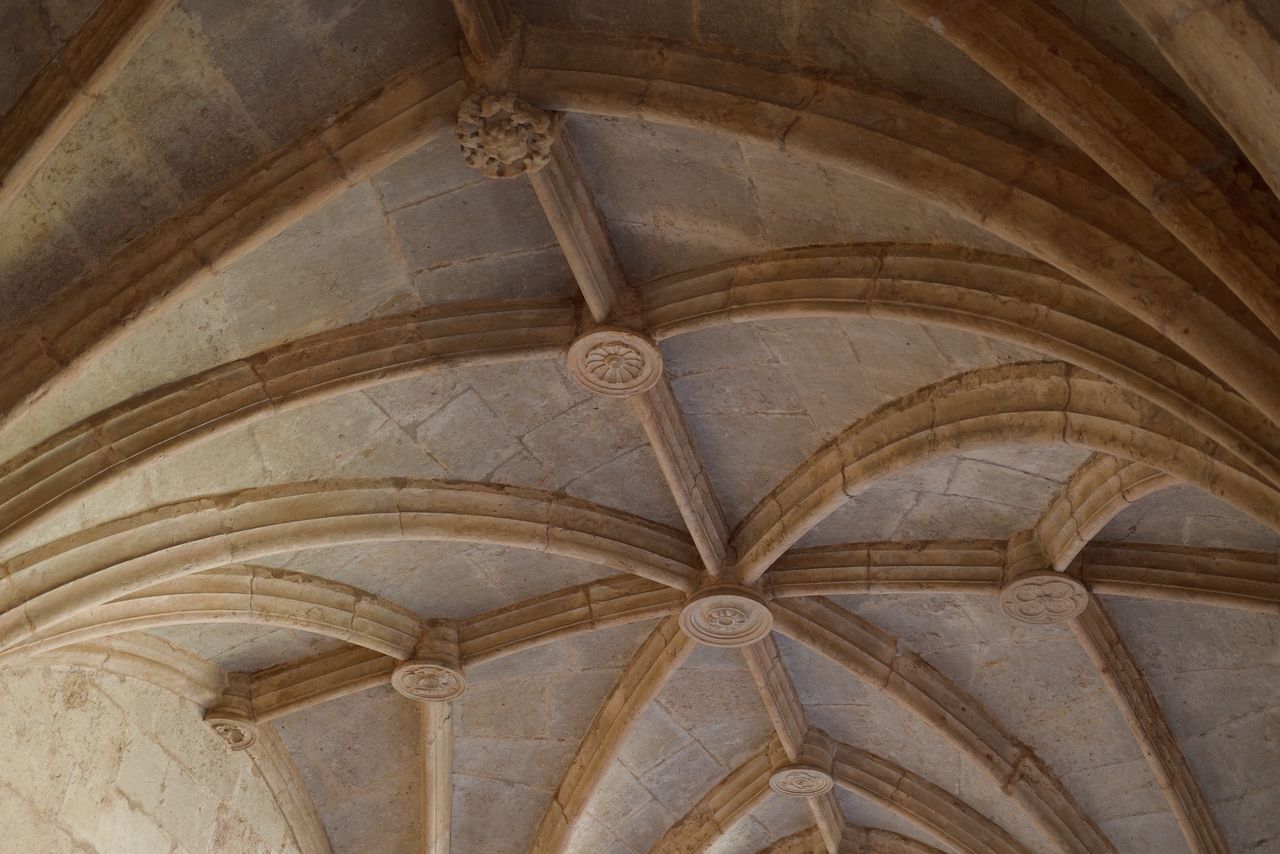 Close-up of a historic rib-vaulted stone ceiling with carved circular bosses.