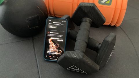 The Pump app on a phone surrounded by fitness equipment