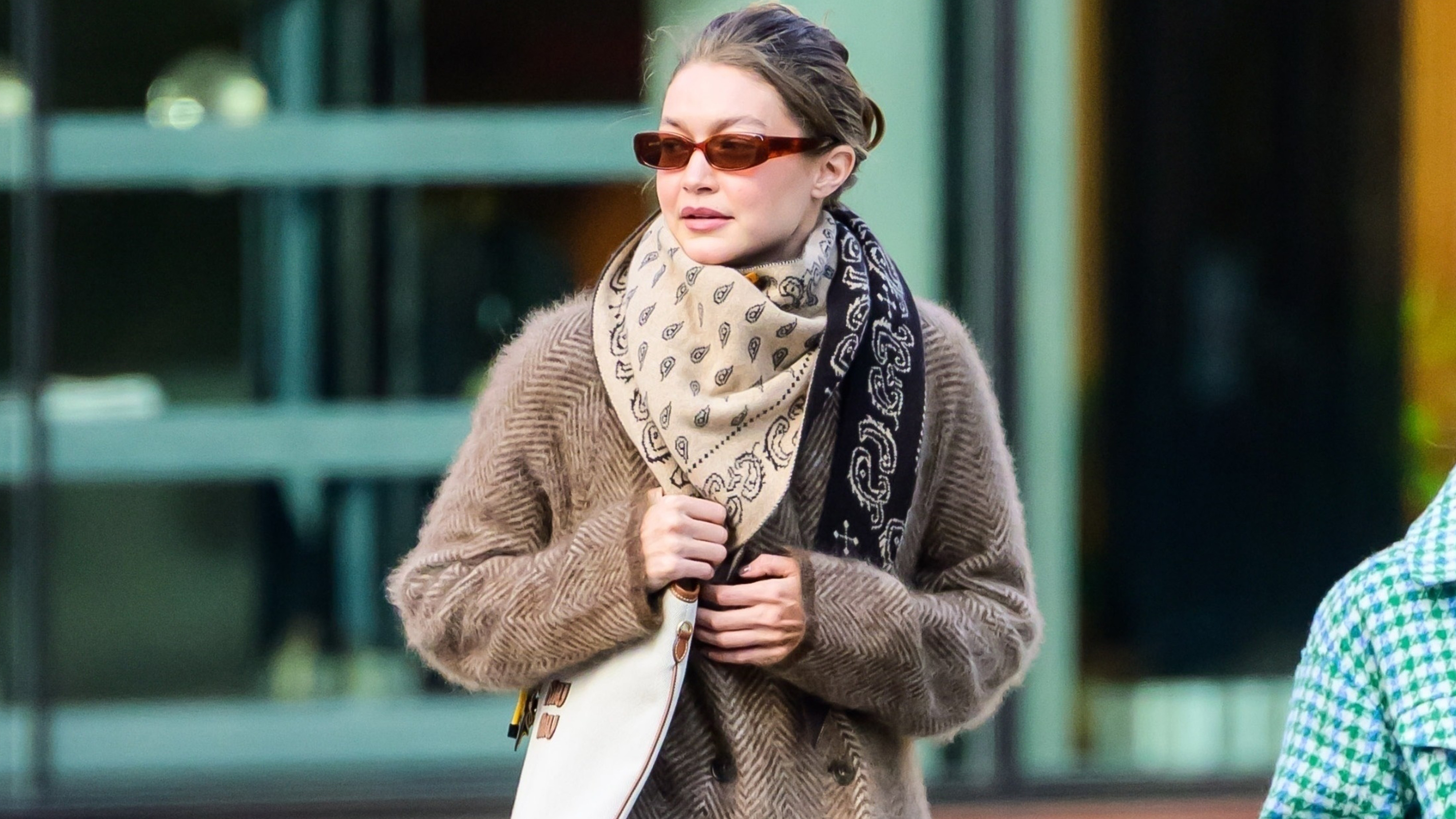 Gigi hadid wears a silk scarf, miu miu bag, and a double breasted wool coat.
