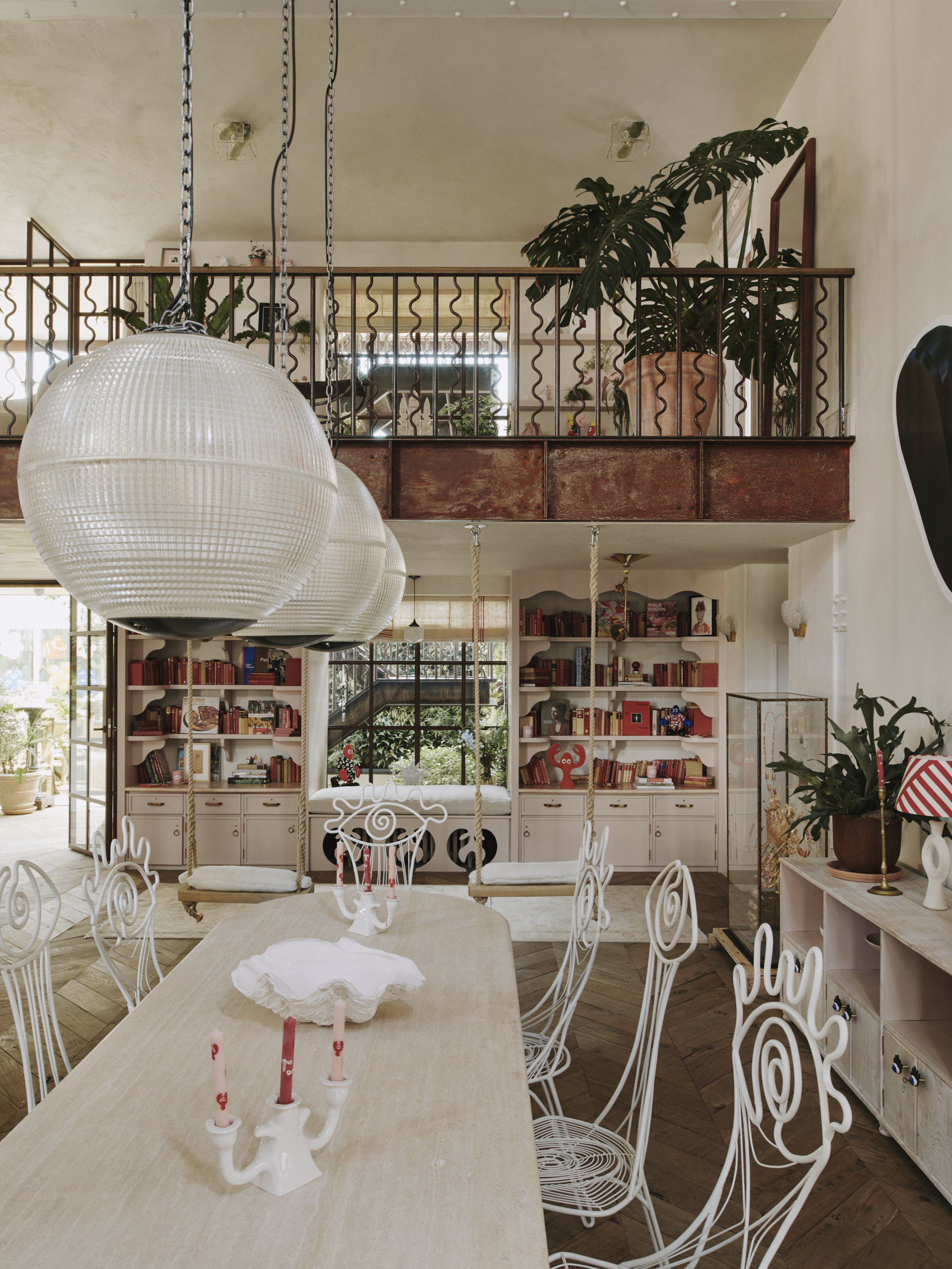 A living room overlooked by a balcony and leafy plants, and with lobster themed bookshelves.