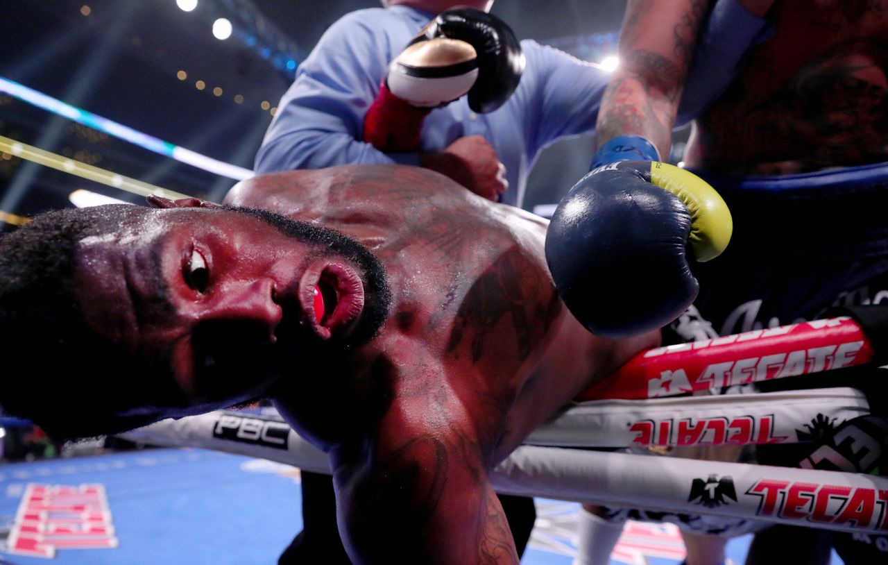 A boxer falls out of the ring after being hit.