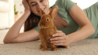 Woman lying next to a bunny on the floor