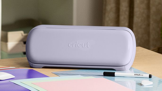 Cricut Joy Xtra in lavender on a desk with card on it and a pen