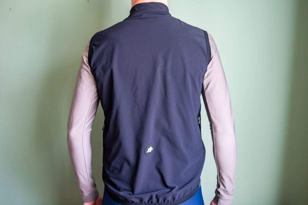 A man wearing a black Assos Tactica gilet over a grey long sleeve shirt
