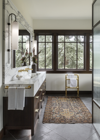 A bathroom with gold fittings and a small printed rug