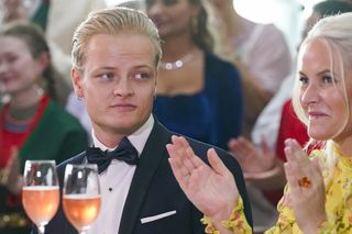 Marius Borg Horby sitting next to his mother Crown Princess Mette-Marit wearing a tuxedo and looking at her as she claps