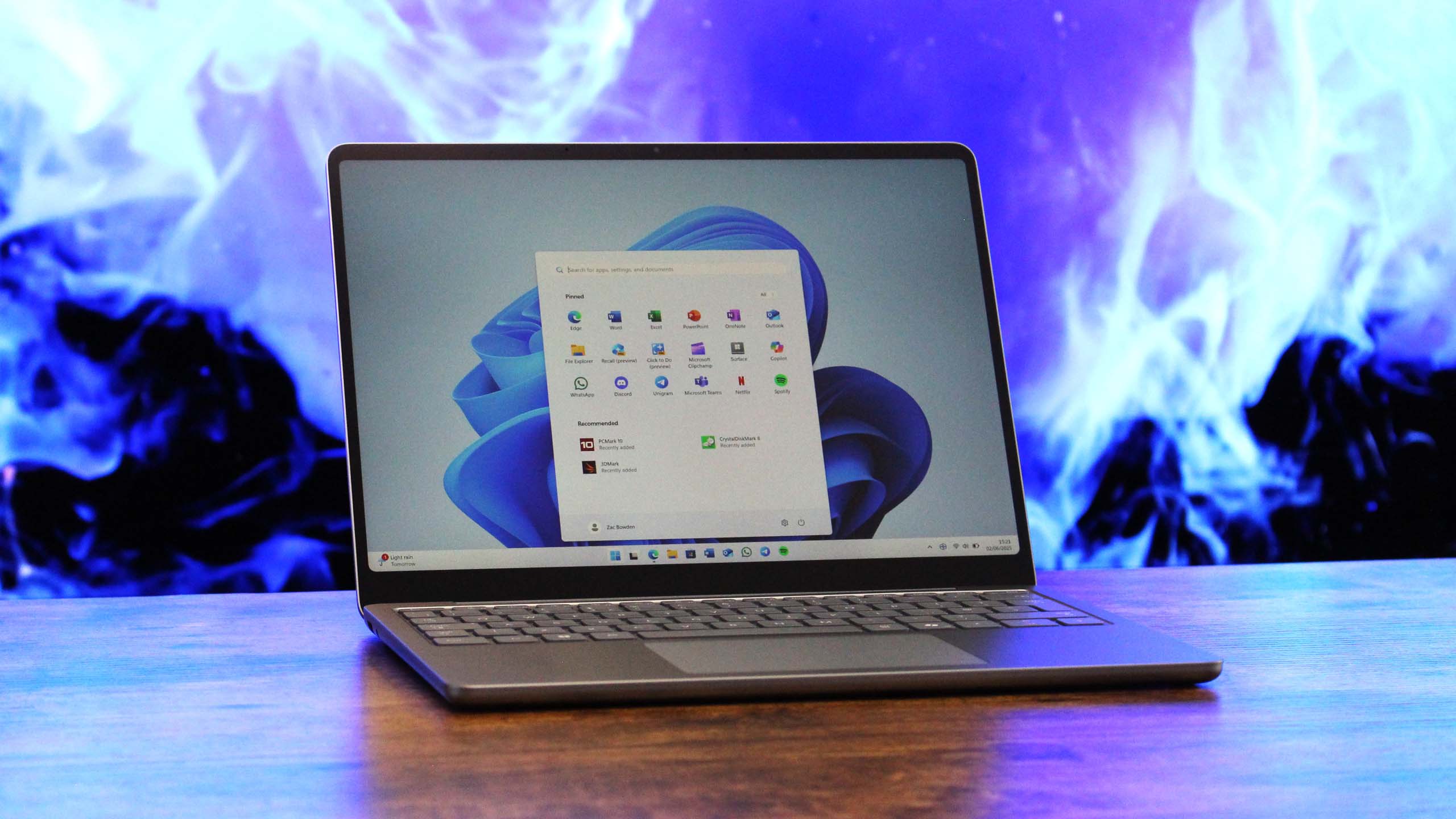 Surface Laptop 13-inch open on a wooden table in front of an abstract background.