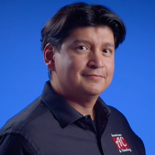 Headshot of Omero Flores wearing dark blue polo shirt with American AC & Heating logo, against blue background.