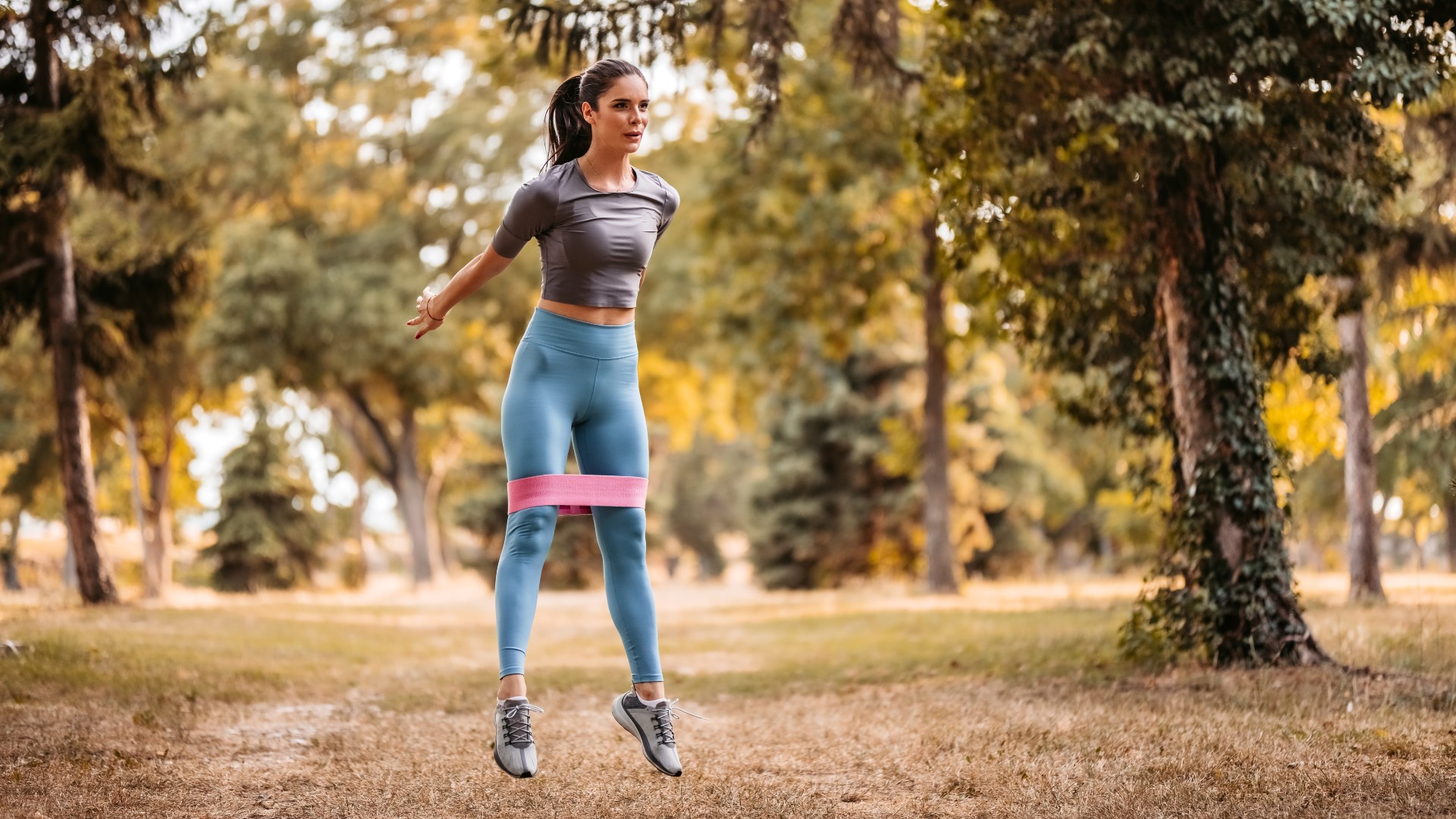 Young woman in park using resistance band