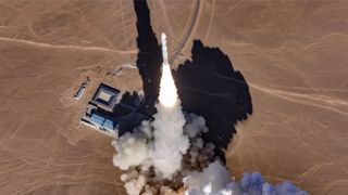 aerial view of a white rocket launching in a desert landscape.