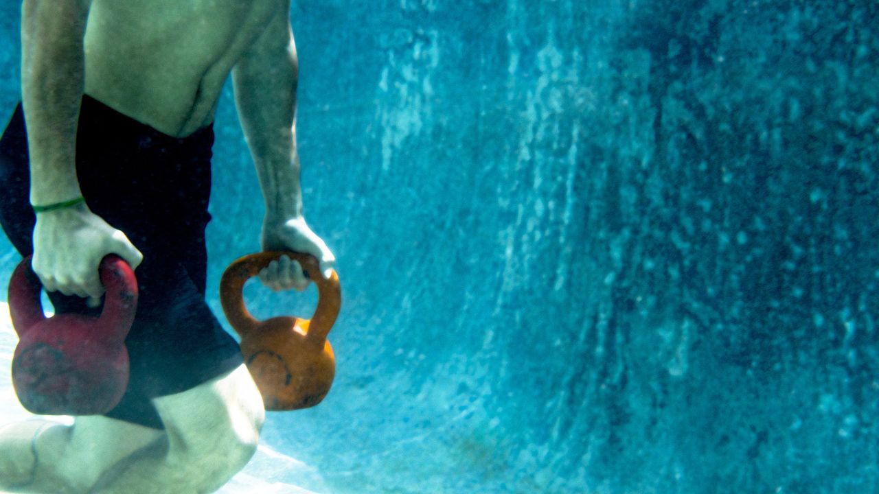 Man carrying kettlebells underwater