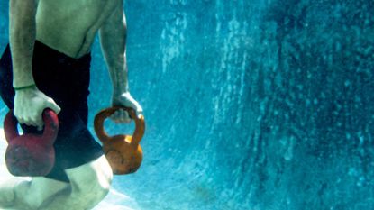 Man carrying kettlebells underwater