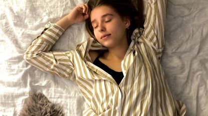 Woman lying on her back on a mattress wearing stripy pyjamas