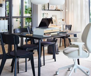 black dining table with office chair pulled up and laptop stand on table