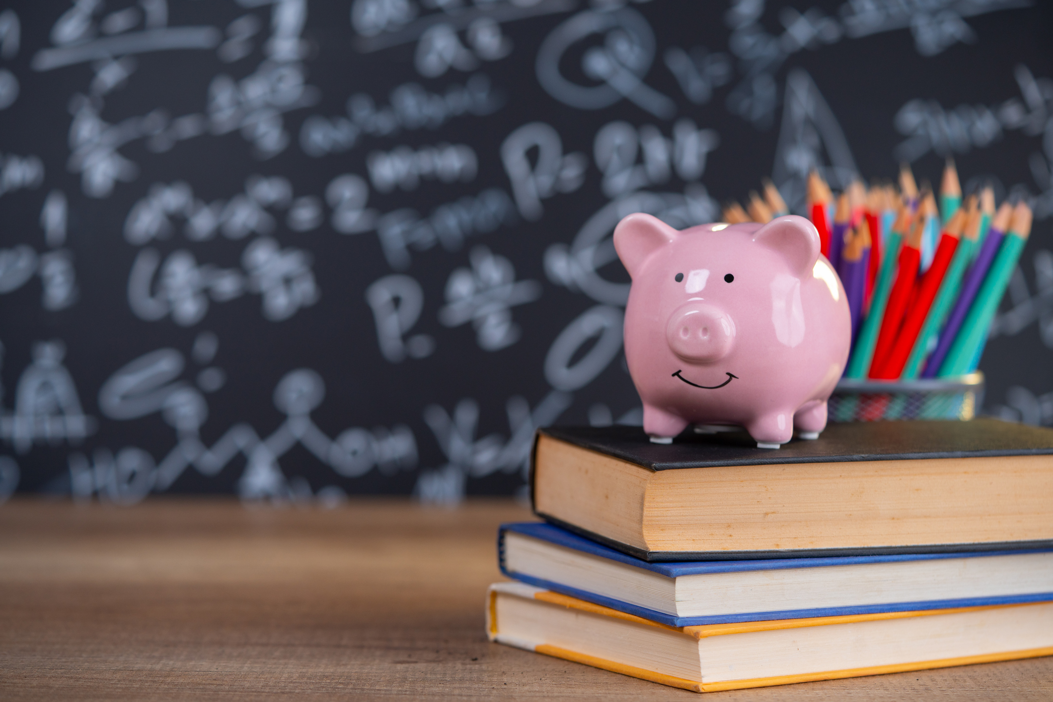 a piggy bank rests on top of a stack of books in classroom