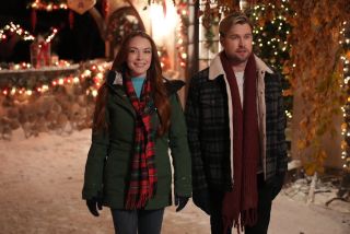 Lindsay Lohan and Chord Overstreet walking in outdoor Christmas setting in Netflix movie