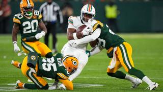 Tight end Jonnu Smith #9 of the Miami Dolphins is tackled by cornerback Keisean Nixon #25 of the Green Bay Packers and safety Xavier McKinney #29 during the first half of an NFL football game, at Lambeau Field on November 28, 2024 in Green Bay, Wisconsin.