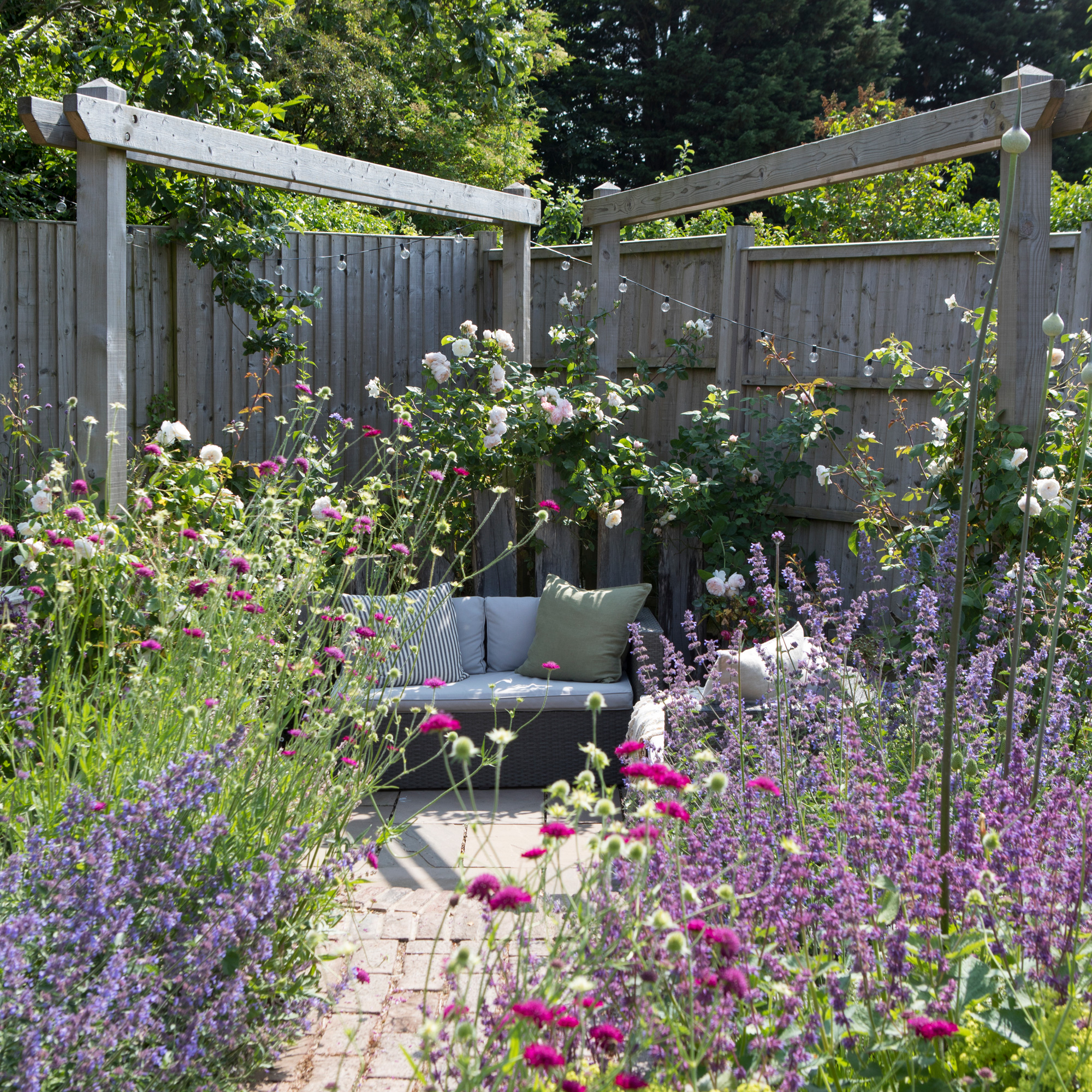 country cottage garden with plenty of planting including lavender and a corner seating area with pergola