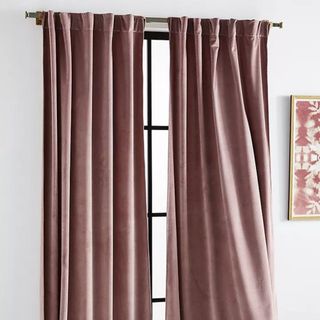 A pair of mauve curtains hanging over a window
