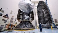 a large silver and black spacecraft is seen inside a large white hangar 