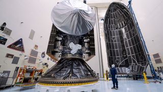 a large silver and black spacecraft is seen inside a large white hangar 