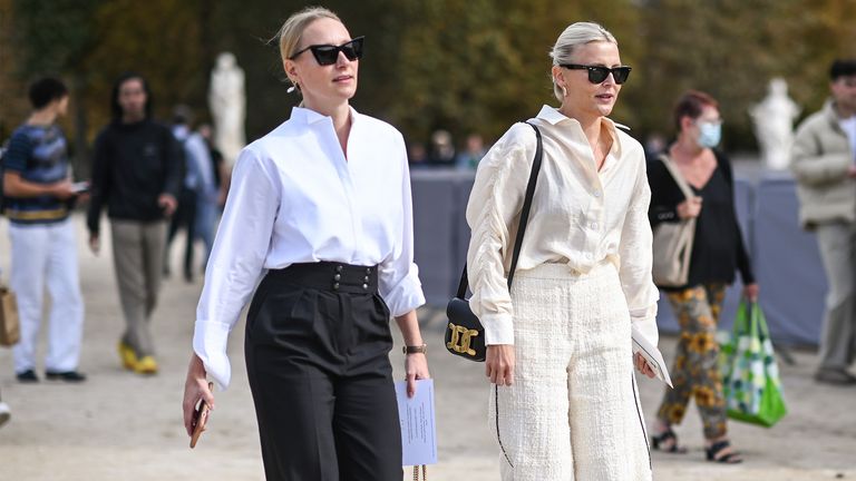 Guests seen wearing Dior blouses and pants with Dior black bags outside the Christian Dior show during Paris Fashion Week S/S 2022 on September 28, 2021 in Paris, France