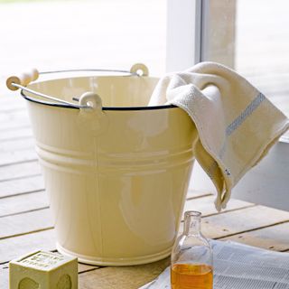 Cream enamel bucket with soft cloth hanging over the edge