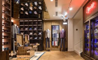 Luxury clothing store, with dark brown shelves filled with dress shirts, and suits displayed on mannequins.