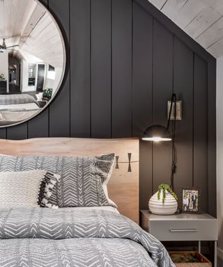Black painted feature paneled wall in bedroom with white patterned bedding