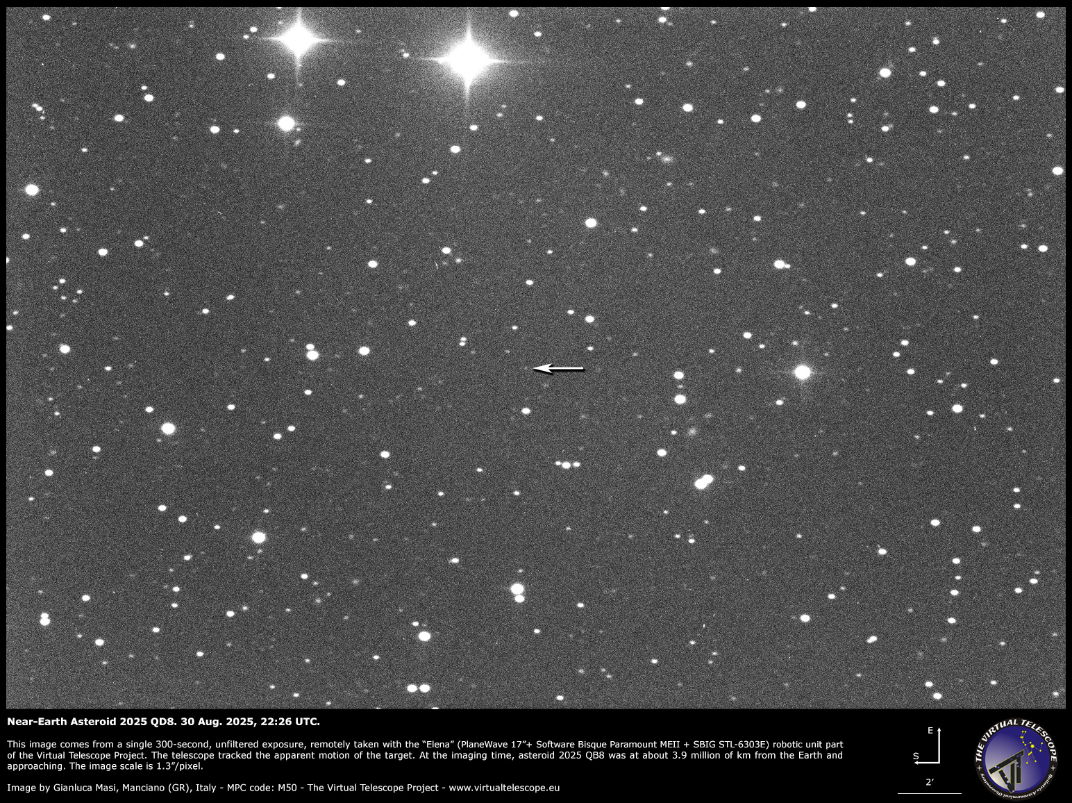 White points of light representing stars are visible against a dark background. A white arrow points to the position of a point of light representing a distant asteroid.