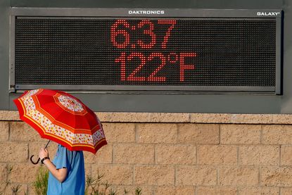 Man walks past sign showing the time and the temperature.