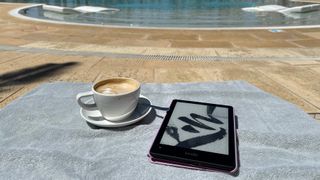 Kindle Paperwhite on sun lounger next to a cup of coffee