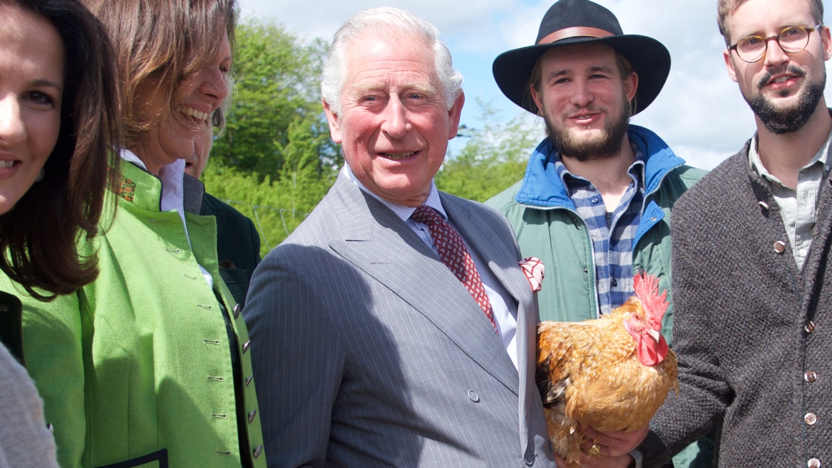 King Charles holds a chicken alongside Sophie Schweinsfurth and Mathias Stinglwagner during a visit to the organic farm Herrmannsdorfer Landwerkstaetten on May 10, 2019